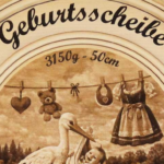 Traditionelle Geburtsscheibe aus lackiertem Ahornholz mit warmen Brauntönen der Brandmalerei und liebevollen Details rund um das Baby.